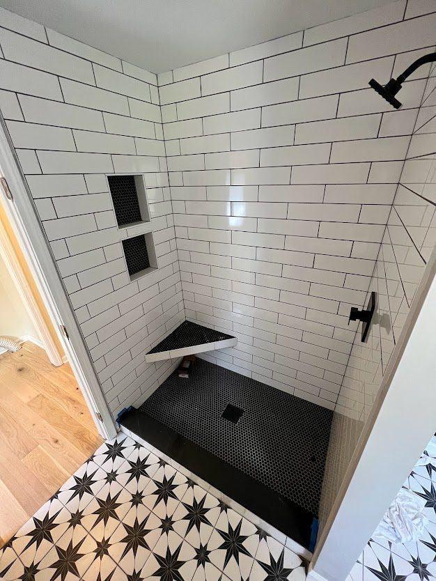Custom white subway tile shower with black penny-tile floor, bathroom remodel