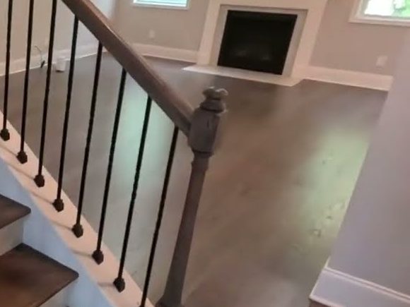Stair railing and gray-stained red oak floor near a fireplace, hardwood installation in Canton, GA