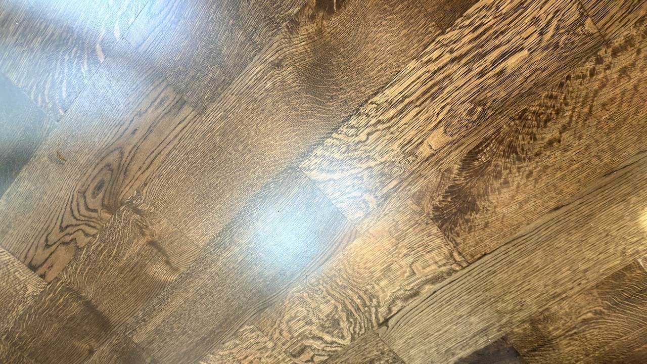 Close-up of white oak plank grain under a freshly applied floor finish, showing the sheen