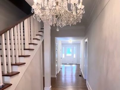 Hallway with a chandelier, staircase and stained hardwood floor in a 1940 home, refinishing in Marietta, GA