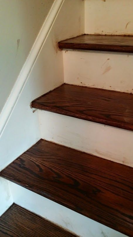 Darker stain shows on the adjacent white risers and skirt boards, waiting on a painter's touch-up.