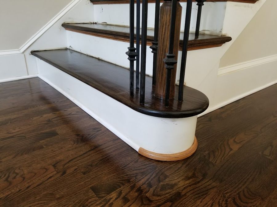A refinished stair base — the quarter round and skirt still need a painter's touch-up.