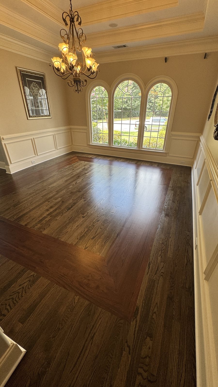 Dining room with red oak hardwood floor in Dark Walnut stain and matte finish, tray ceiling, chandelier and inlay border