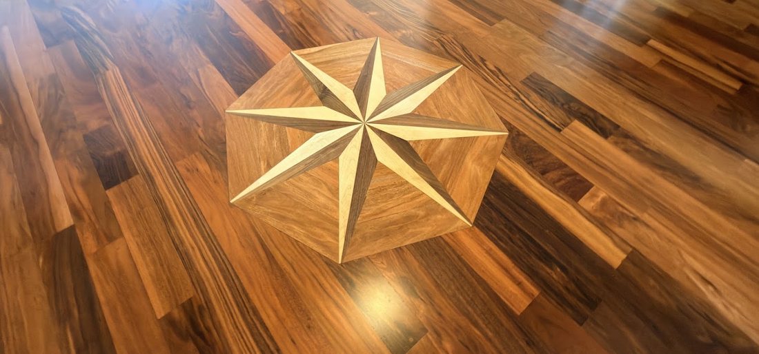 Eight-point compass rose medallion inlaid into a tigerwood floor, installed and finished by The Hardwood Guys