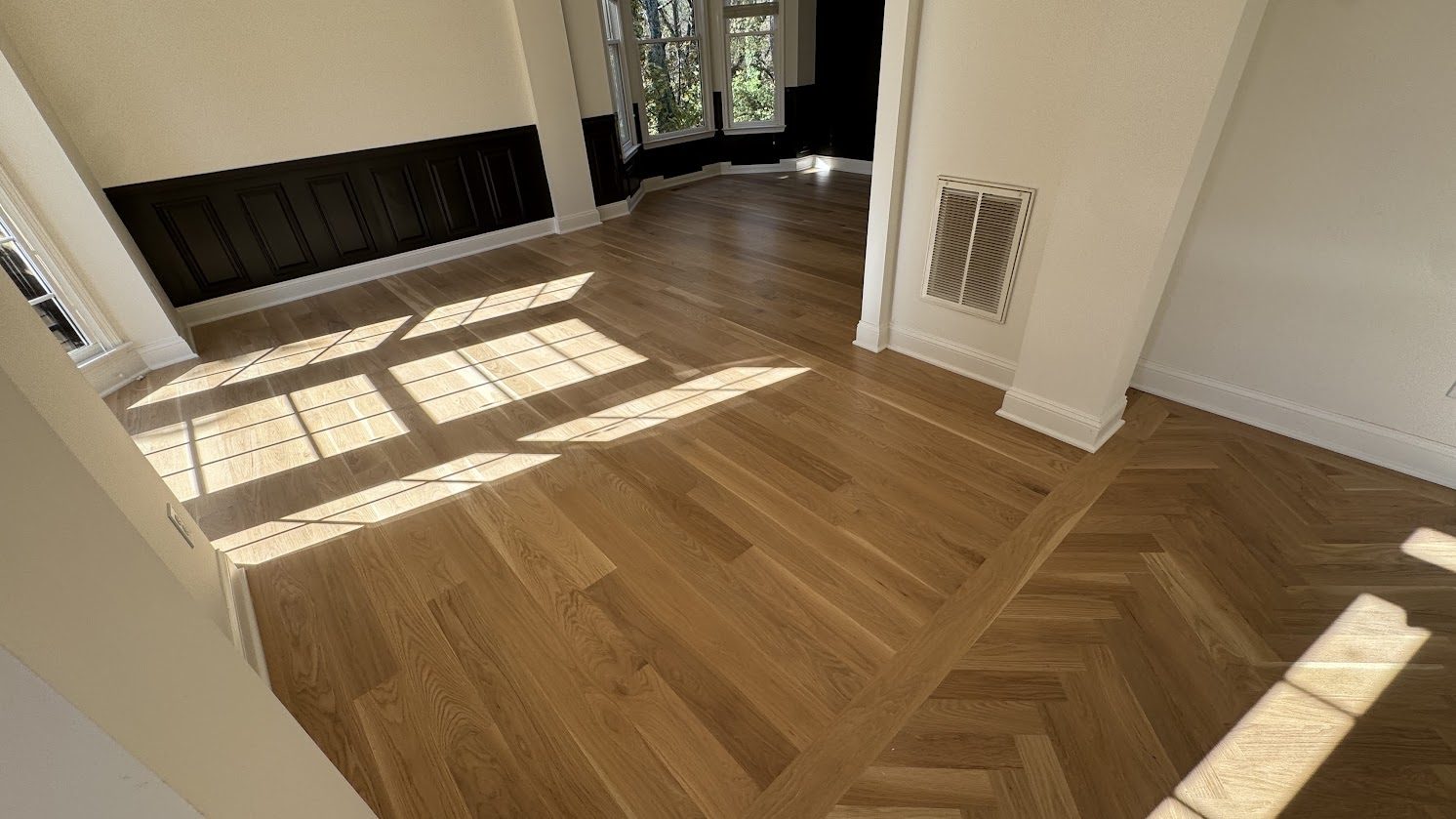 New white oak hardwood flooring with a herringbone inlay border, installed by The Hardwood Guys