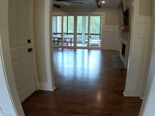 Stained red oak floor seen through a doorway into an open living area, Provincial stain refinishing in Woodstock, GA