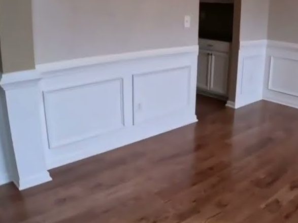 Stained hardwood floor beside white wainscoting in a dining area, hardwood installation and refinishing in Woodstock, GA